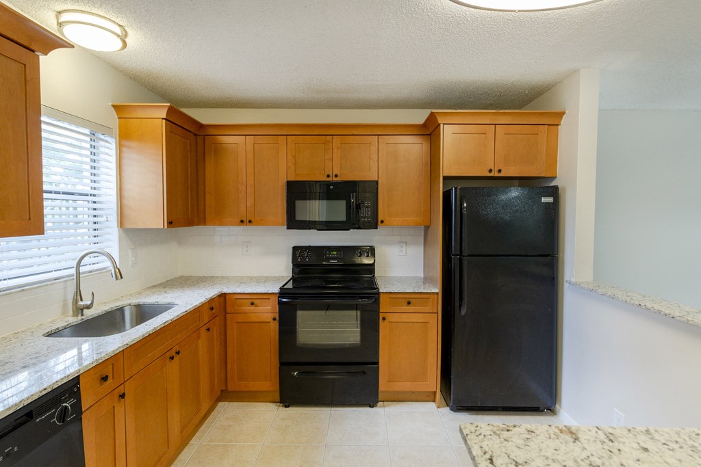 A kitchen with black appliances and wooden cabinets.